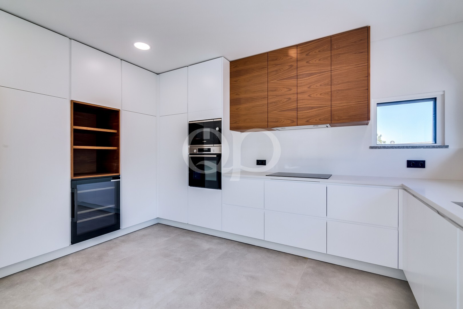 Modern white kitchen with handleless cabinets, oak upper cabinets, and built-in oven/microwave.