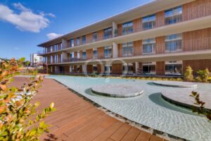 Modern apartment building with balconies overlooking a shallow pool and wooden deck.