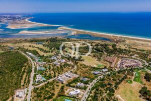 Vista aérea de uma zona balnear costeira com o oceano azul, praias arenosas e casas espalhadas por entre paisagens verdes e estradas. "O texto alternativo pode ser complexo; vamos mantê-lo conciso."