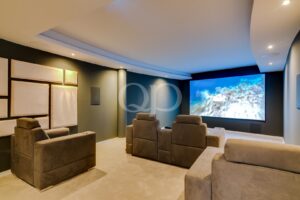 Home theater with a large screen displaying an underwater scene and plush brown seating around.