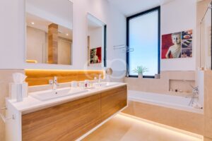 Modern bathroom with dual sinks, wooden vanity, and large mirrors reflecting warm lighting
