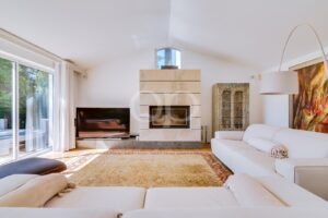 Bright modern living room with a white sectional sofa, a stone fireplace centerpiece, and a large sliding glass door to the patio on the left