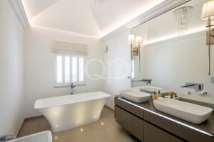 Modern white bathroom with a freestanding tub and double vessel sinks under a large mirror.