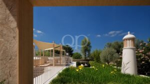 Pátio exterior moderno com velas de sombra bege, postes de madeira, corrimão branco e um jardim exuberante sob um céu azul límpido