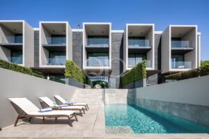 ” Complexe résidentiel moderne doté de balcons vitrés et d'un espace rectangulaire au bord de la piscine au rez-de-chaussée, avec des chaises longues le long de la piscine. »], ,