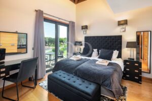 Chambre d'hôtel avec deux lits jumeaux, une tête de lit capitonnée de couleur sombre et un balcon accessible par des baies vitrées coulissantes