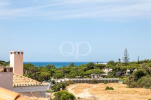Vue d'une ville côtière avec ses toits de tuiles, ses oliviers et la mer bleue à l'horizon, sous un ciel dégagé.