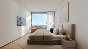 Modern bedroom with gray upholstered bed, wall-mounted TV, and a balcony door opening to an outdoor seating area in a bright, minimal space.