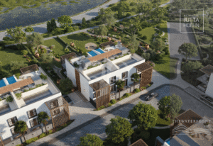 Vue aérienne d'un complexe immobilier moderne composé de maisons de ville blanches, avec des piscines sur les toits, des treillis en bois et un aménagement paysager luxuriant le long d'un front de mer ombragé.