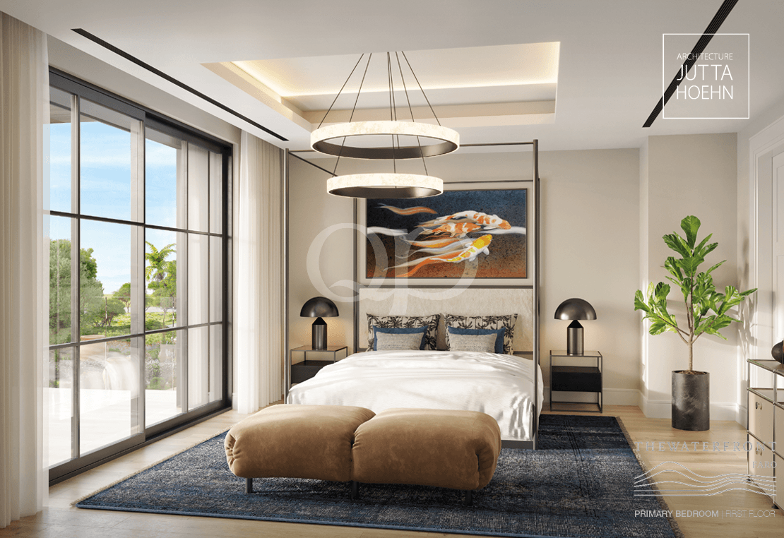 Quarto moderno e luminoso com uma cama de dossel, luzes circulares pendentes, um tapete azul-escuro e uma otomana castanha aos pés da cama.