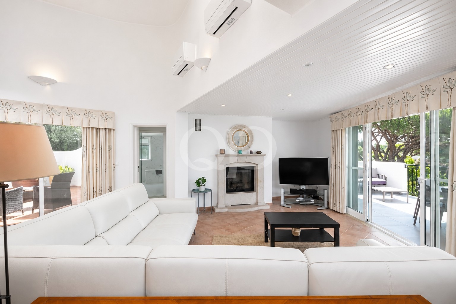 Bright living room with a white sectional sofa, fireplace, and large sliding glass doors to the patio area.