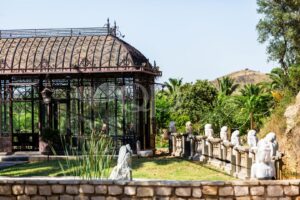 Ornamental glass pavilion surrounded by mature palms and landscaped gardens