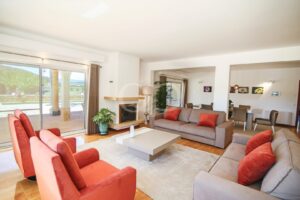 Sitting room with fireplace, large windows and contemporary neutral furnishings