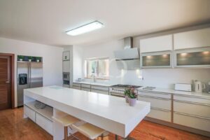 Modern kitchen with central island, integrated appliances and sleek white cabinetry