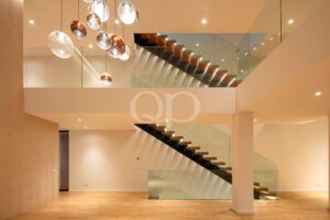 Escadaria suspensa com balaustrada de vidro e iluminação decorativa suspensa