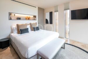 Quarto com cabeceira integrada, mobiliário contemporâneo e acesso ao terraço