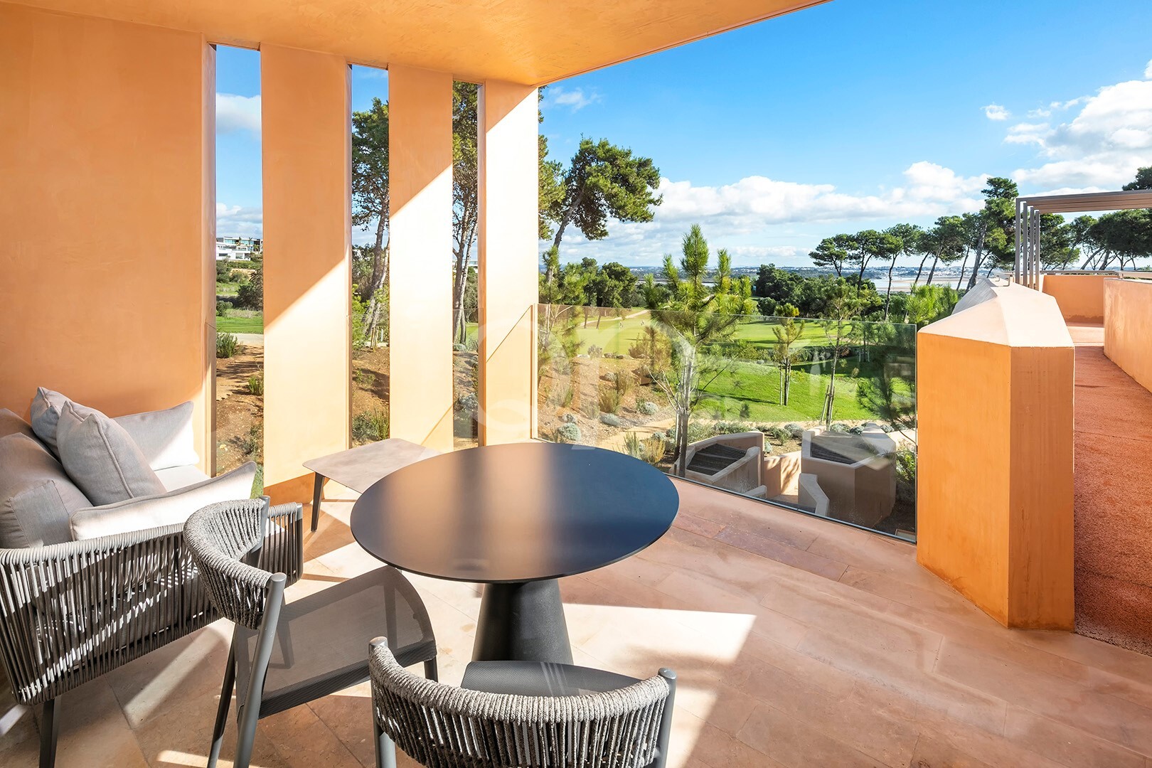 Terrasse privée avec coin repas en plein air donnant sur des jardins paysagers et des pins