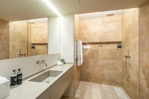 Casa de banho luminosa e luxuosa, com cabina de duche em vidro, chuveiro tipo «rainfall» e um elegante lavatório com armário