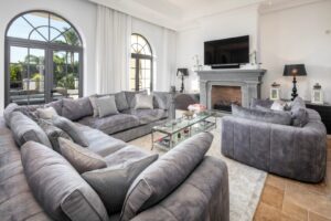 Wohnzimmer mit Ecksofas, einem Couchtisch aus Glas und einem Kamin