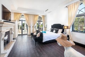Schlafzimmer mit gewölbten Terrassentüren, dunklem Bodenbelag und einem gepolsterten Bett