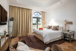 Schlafzimmer mit Bogenfenstern, Zugang zur Terrasse und neutraler Einrichtung