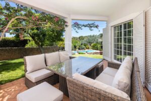 Großzügige überdachte Terrasse mit eleganter Sitzecke im Freien, üppigen Gärten und einladendem Blick auf den Pool