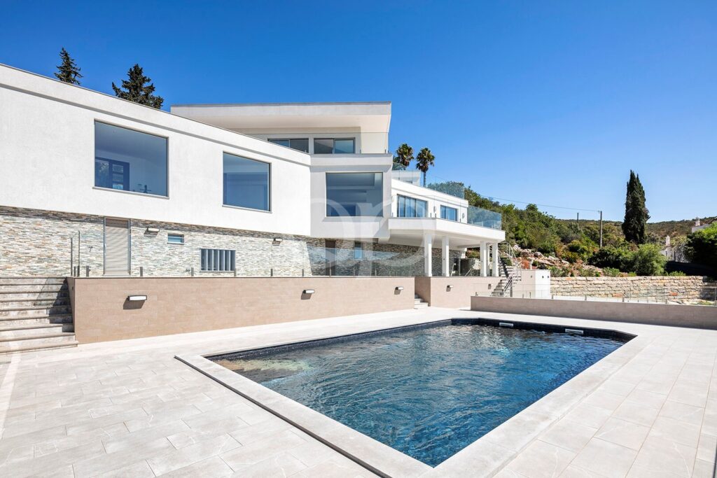 Piscine privée entourée de vastes terrasses et d'une villa à l'architecture contemporaine