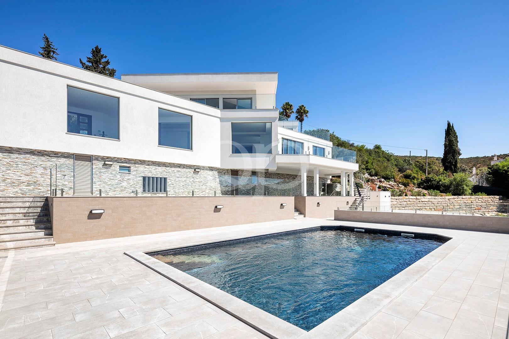 Piscine privée entourée de vastes terrasses et d'une villa à l'architecture contemporaine