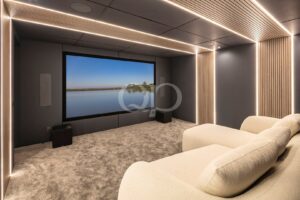 Sala de cinema privada com assentos confortáveis, iluminação ambiente e ecrã grande