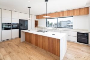 Cozinha contemporânea com ilha central, eletrodomésticos embutidos e armários em madeira