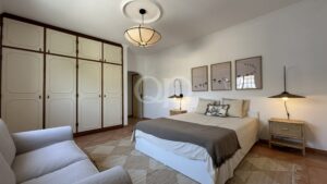 Bedroom with two neatly made beds, beige bedding, and wicker nightstands under matching lamps.