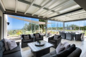 Covered outdoor lounge with glass enclosure and garden views