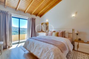 Quarto elegante com um acolhedor pavimento e teto em madeira, que oferece vistas panorâmicas sobre o campo