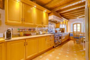 Cuisine traditionnelle avec des meubles en bois, des plans de travail carrelés et un plafond avec poutres apparentes