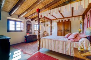 Chambre avec poutres apparentes, lit à baldaquin et carrelage traditionnel