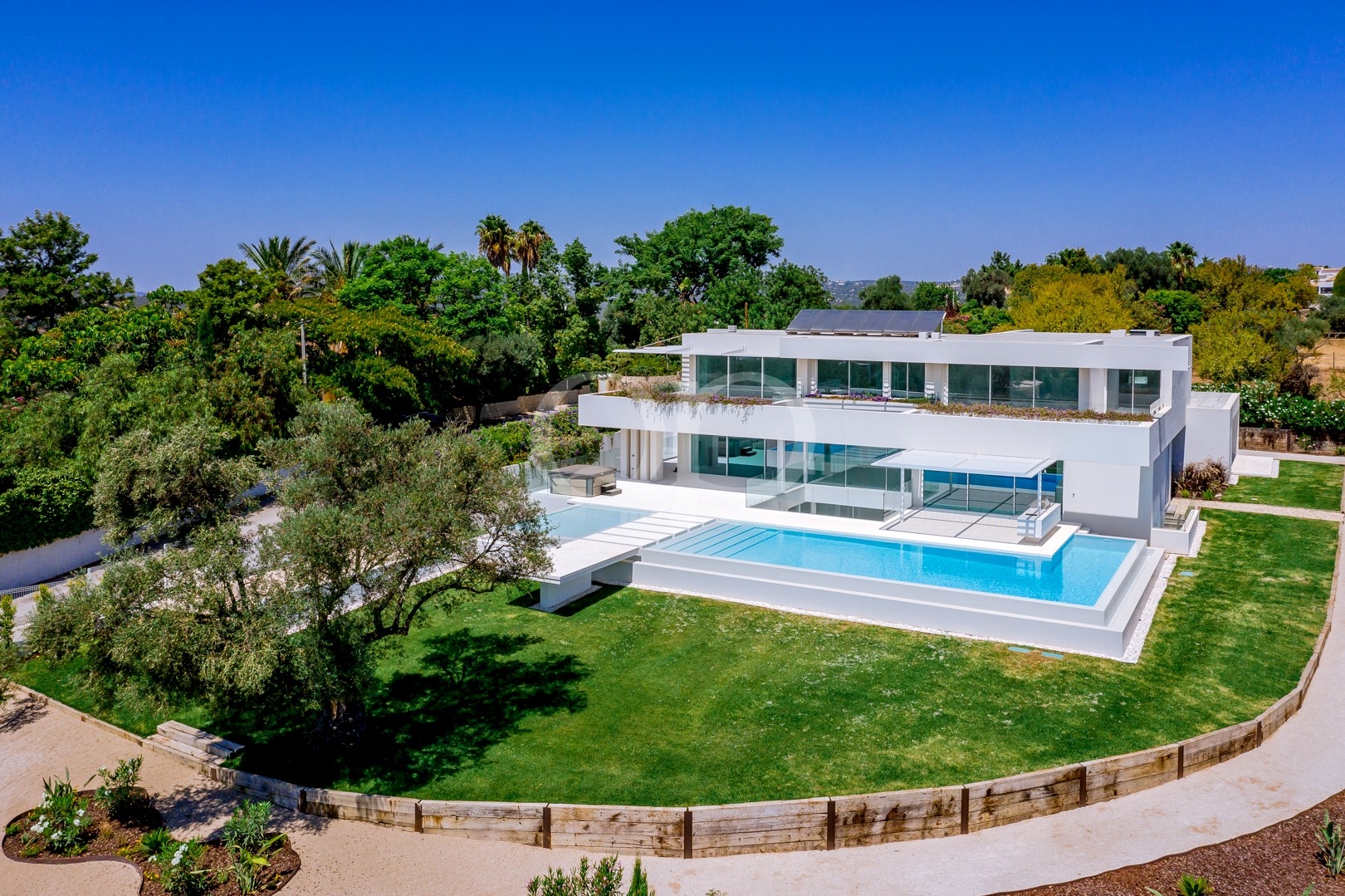 Luftaufnahme einer modernen Villa mit Swimmingpool und gepflegten Gärten