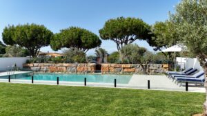 Private swimming pool with landscaped gardens, stone walls and mature pine trees