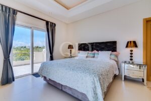 Spacious bedroom with high-ceilings and a balcony overlooking countryside views