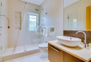 Bright, contemporary bathroom featuring a walk-in glass shower, rainfall showerhead, and elegant vanity