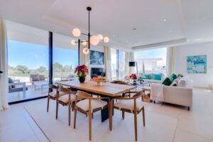 Salle à manger ouverte dotée de baies vitrées allant du sol au plafond et donnant accès à la terrasse