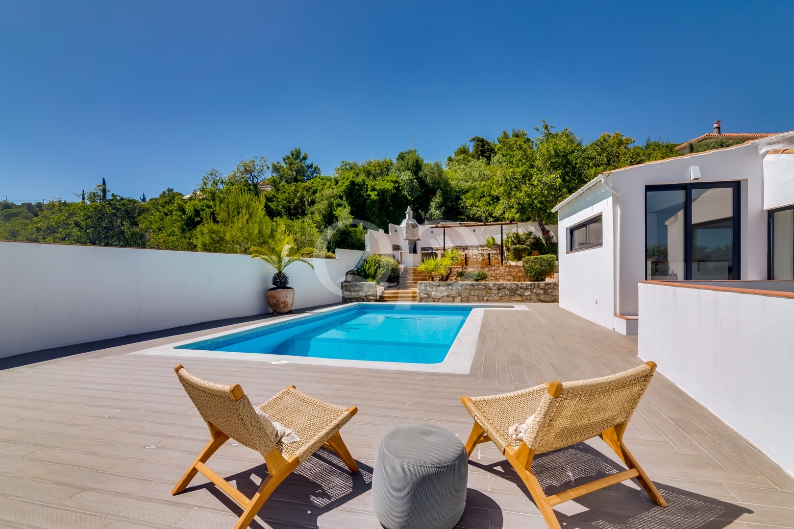 Private swimming pool with spacious sun terrace and surrounding mature greenery