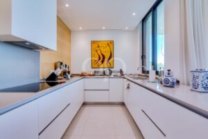 Cuisine équipée moderne avec des appareils électroménagers encastrés, des meubles épurés et de grandes fenêtres
