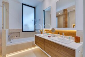 Salle de bains moderne avec double vasque, baignoire, meubles en bois et lumière naturelle