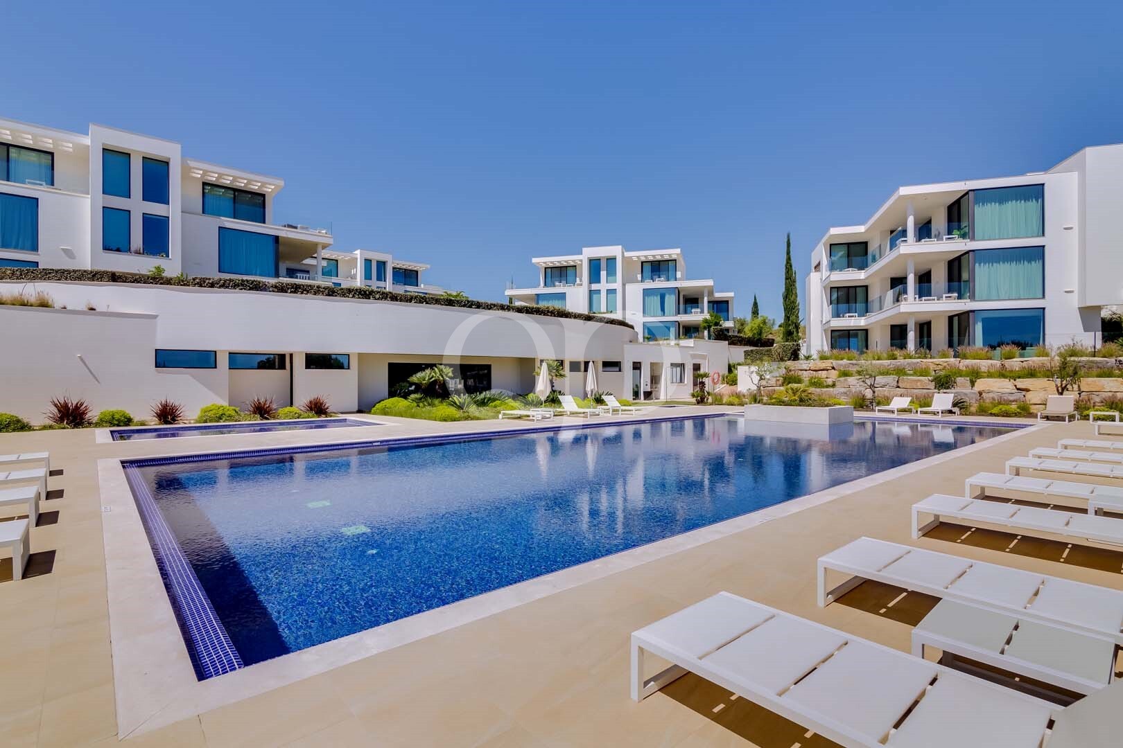 Piscine collective avec terrasse ensoleillée et complexe d'appartements au style contemporain