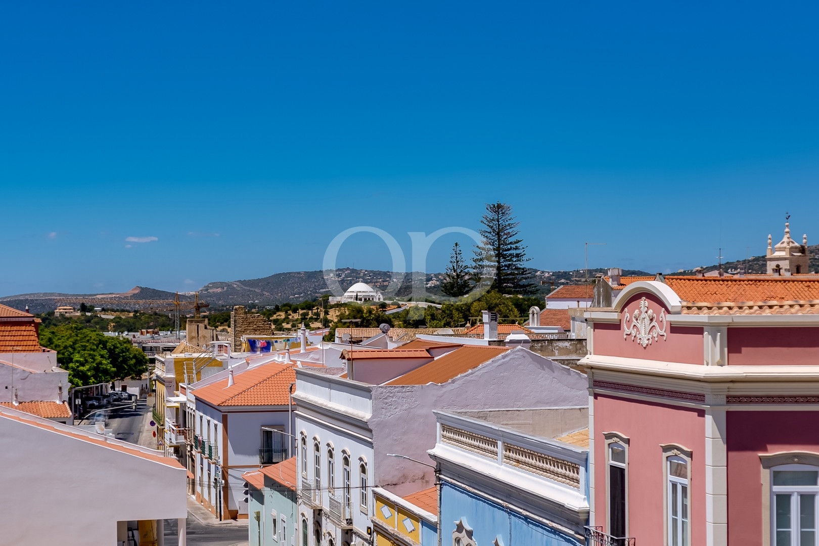 Panoramic views over a charming historic town, colourful rooftops, and surrounding mountains