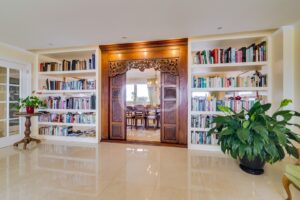 Biblioteca elegante com estantes feitas à medida e uma porta de madeira com belíssimas talhas