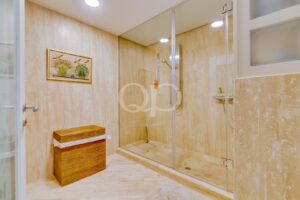 Casa de banho espaçosa com cabina de duche e elegantes acabamentos em pedra natural