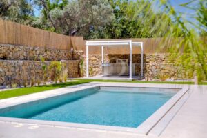 Swimming pool with outdoor kitchen and stone boundary wall