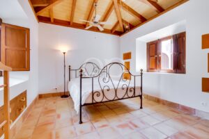 Schlafzimmer mit schmiedeeisernem Bett und sichtbarer Holzdecke