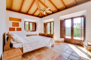 Schlafzimmer mit sichtbarer Holzdecke und Zugang zur Terrasse